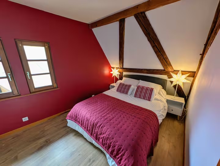 Chambre spacieuse avec grand lit aux plafonds en pente, drapé de couleurs élégantes et de beaux accessoires, offrant une a...