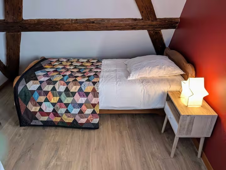 Lieu de repos intime avec un lit double et une coiffeuse au-dessus du fauteuil.